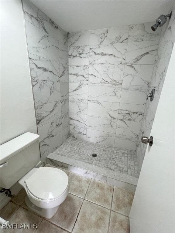 bathroom with tile patterned floors, toilet, and a tile shower