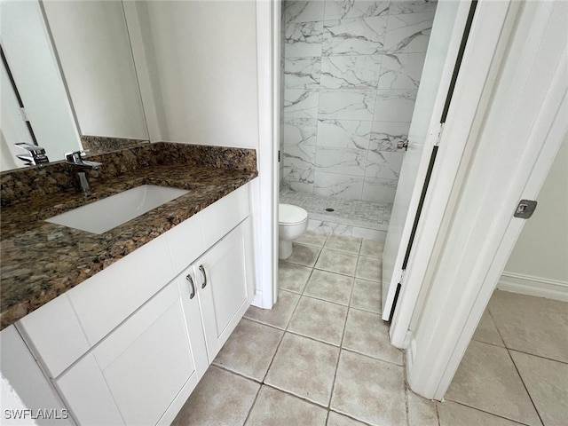 bathroom featuring tile patterned floors, toilet, a tile shower, and vanity