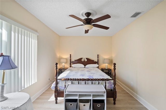 bedroom featuring ceiling fan, light hardwood / wood-style flooring, and a textured ceiling