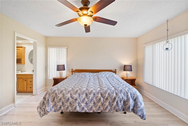 bedroom with ceiling fan, light wood-type flooring, ensuite bath, and a textured ceiling