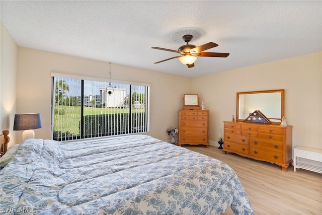 bedroom with ceiling fan, light hardwood / wood-style floors, and a textured ceiling