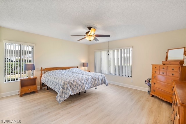 bedroom featuring a textured ceiling, ceiling fan, and light wood-type flooring