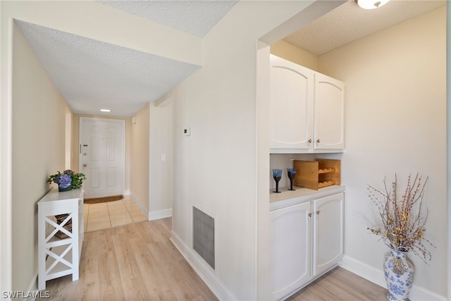 hallway with a textured ceiling and light wood-type flooring