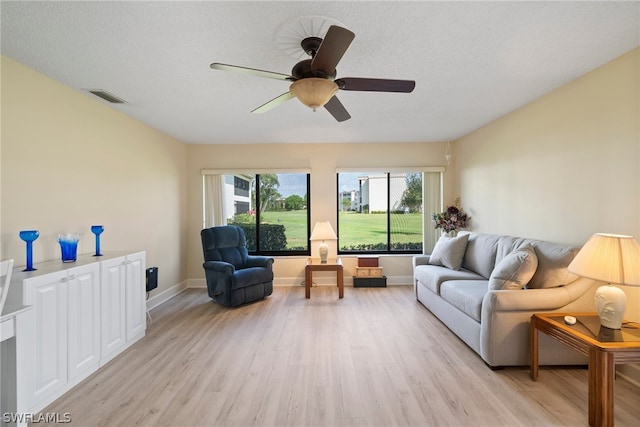 living room with ceiling fan, light hardwood / wood-style floors, and a textured ceiling