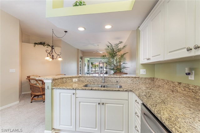 kitchen featuring kitchen peninsula, decorative light fixtures, light colored carpet, sink, and white cabinetry