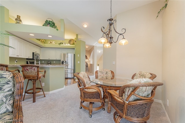 carpeted dining space featuring high vaulted ceiling and a chandelier