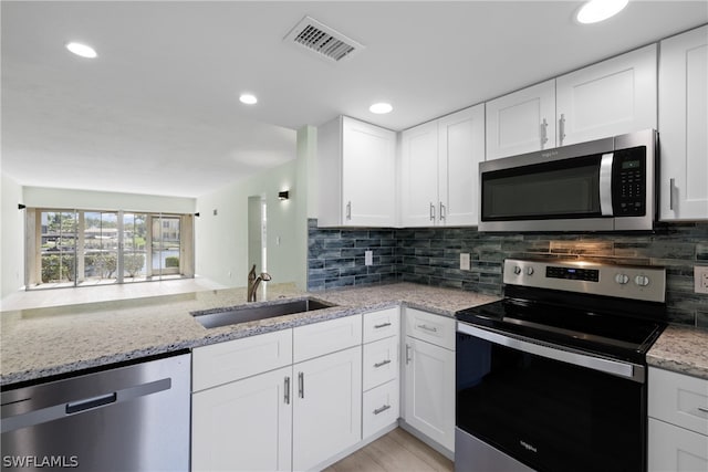 kitchen featuring light stone counters, backsplash, sink, white cabinetry, and appliances with stainless steel finishes