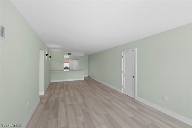 unfurnished living room featuring a barn door and light hardwood / wood-style flooring