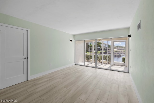 empty room with light hardwood / wood-style floors and a water view