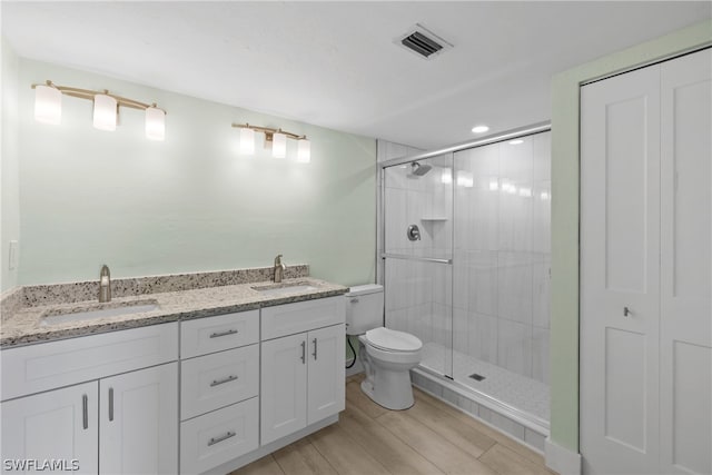 bathroom featuring a shower with door, double vanity, toilet, and wood-type flooring