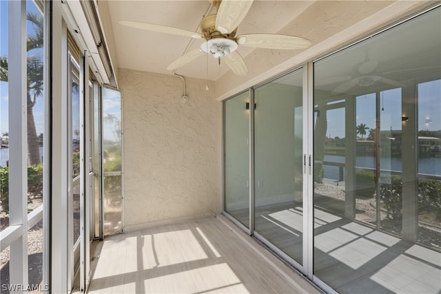 unfurnished sunroom with a water view and ceiling fan