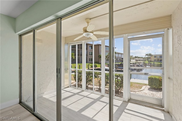 unfurnished sunroom with ceiling fan and a water view