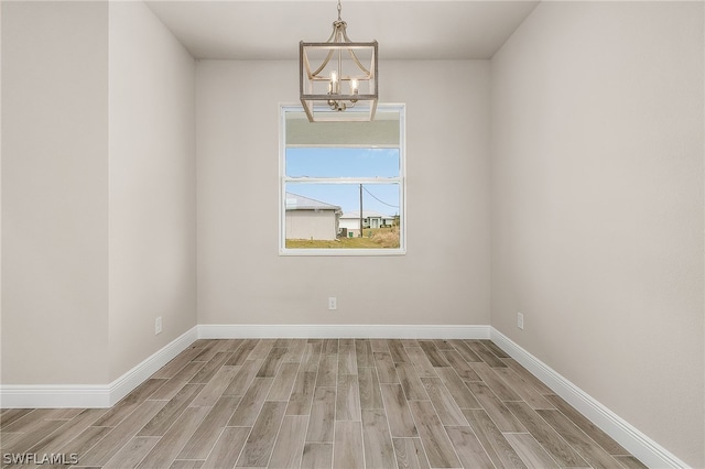 spare room with light wood-type flooring and a chandelier