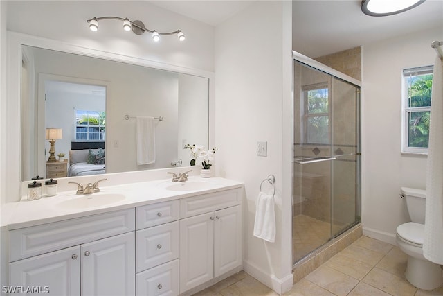 bathroom with plenty of natural light, a shower with shower door, toilet, and double sink vanity