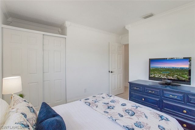 bedroom with a closet, light tile flooring, and ornamental molding