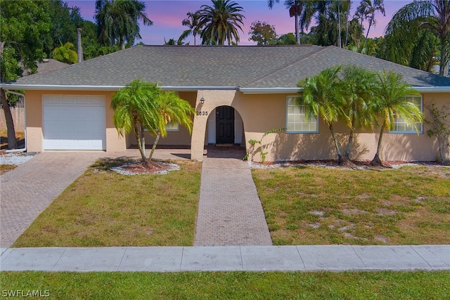 ranch-style home with a garage and a lawn