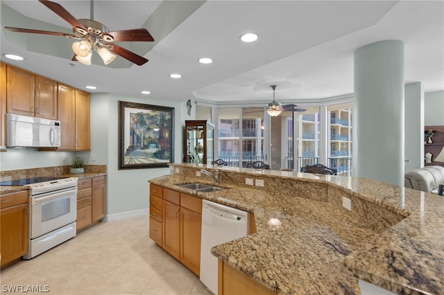 kitchen with sink, light stone counters, hanging light fixtures, light tile patterned floors, and white appliances