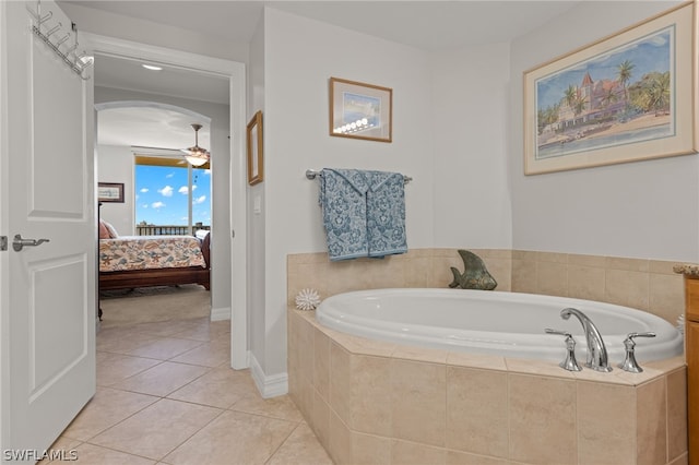 bathroom with tile patterned flooring, a relaxing tiled tub, and ceiling fan