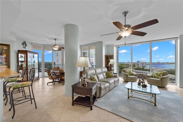 living room with floor to ceiling windows, a water view, a healthy amount of sunlight, and light tile patterned flooring