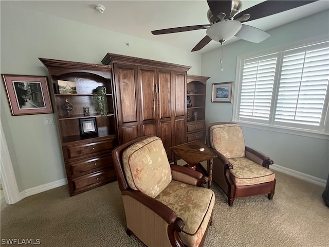 sitting room with ceiling fan and dark carpet