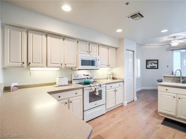 kitchen featuring white appliances, white cabinetry, sink, and light hardwood / wood-style floors