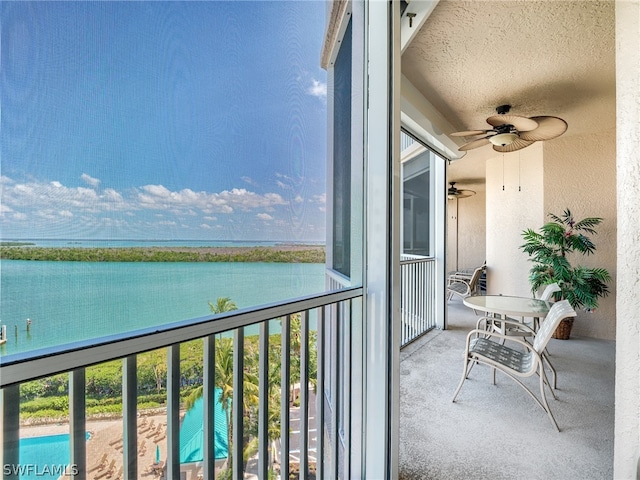 balcony featuring a water view and ceiling fan