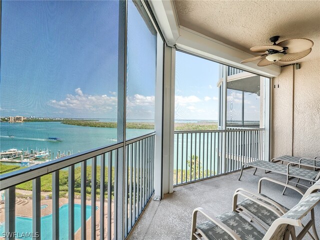 sunroom featuring a water view and ceiling fan