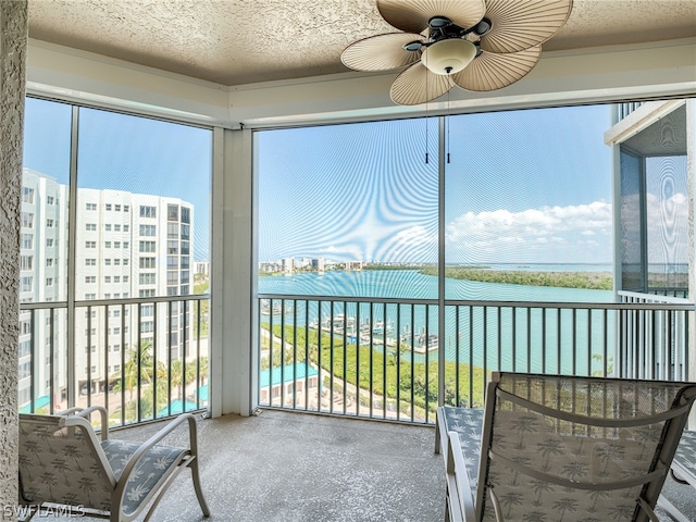 unfurnished sunroom featuring a water view, plenty of natural light, and ceiling fan