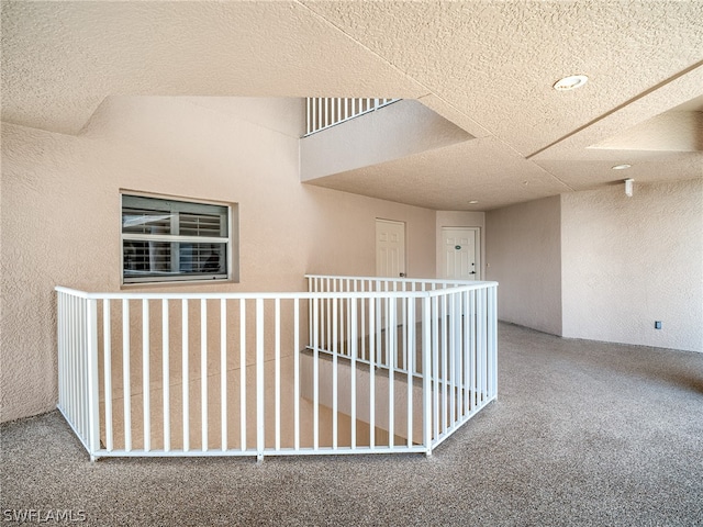 hall featuring carpet floors and a textured ceiling