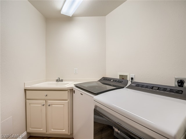 laundry area featuring cabinets, a textured ceiling, washer and clothes dryer, and sink