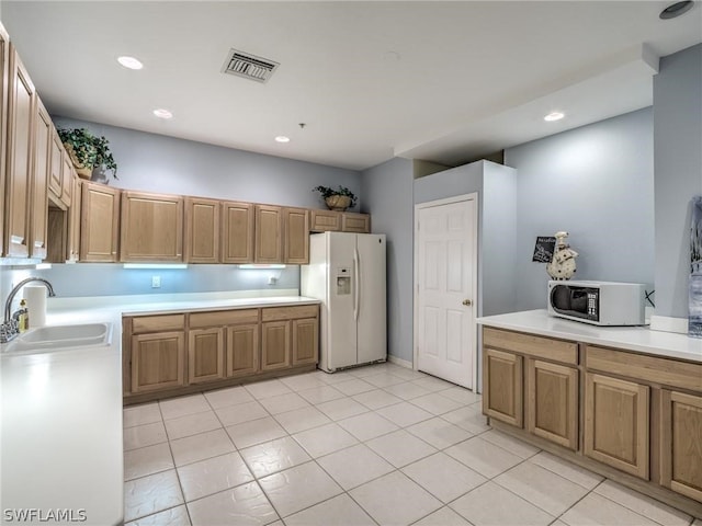 kitchen featuring light tile patterned flooring, white appliances, and sink