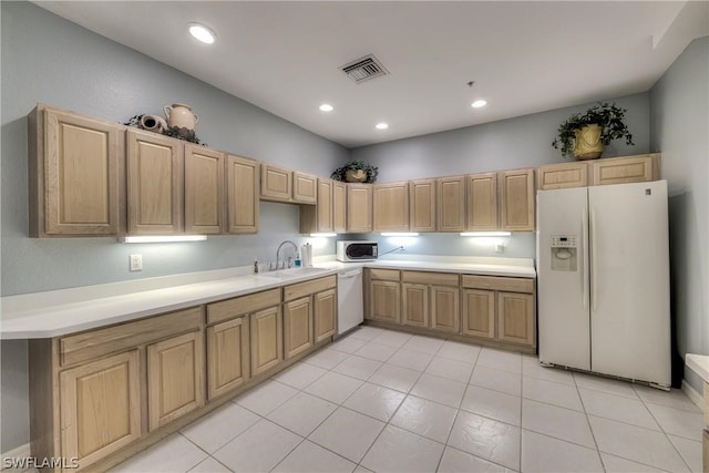 kitchen featuring light tile patterned flooring, light brown cabinetry, white appliances, and sink