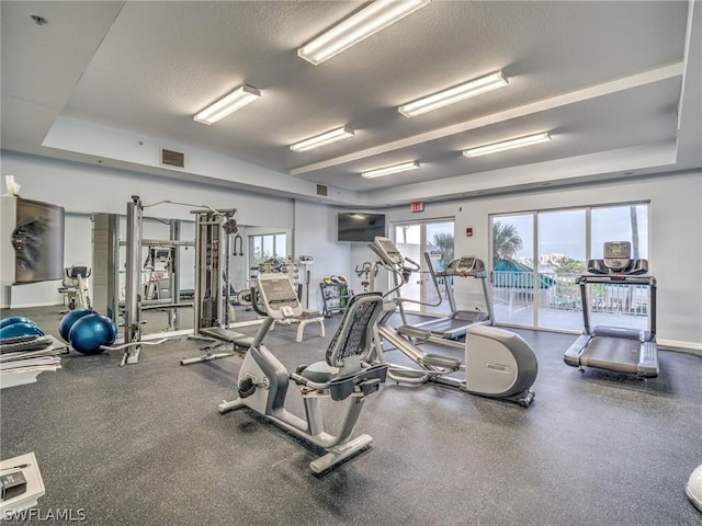 exercise room with a textured ceiling and a tray ceiling