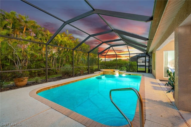 pool at dusk featuring an in ground hot tub, a lanai, and a patio