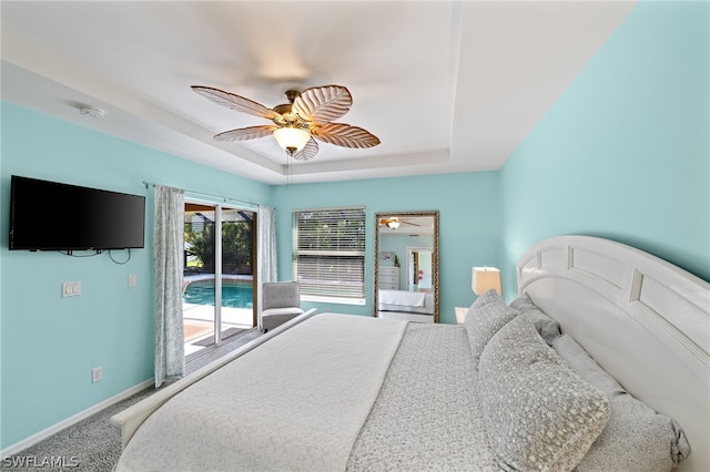 bedroom with ceiling fan, a tray ceiling, carpet, and access to exterior