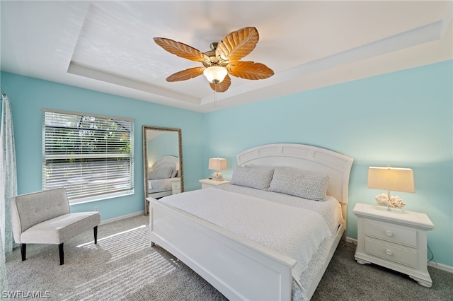 carpeted bedroom with a tray ceiling and ceiling fan