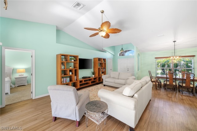 living room with ceiling fan with notable chandelier, vaulted ceiling, and light hardwood / wood-style floors