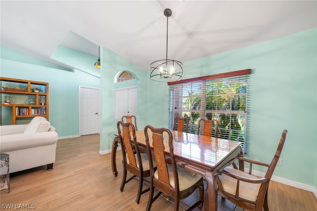 dining room with lofted ceiling, a chandelier, and light wood-type flooring