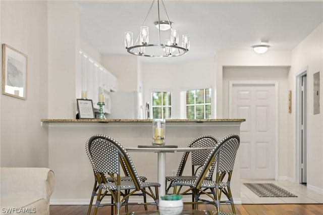 bar featuring light stone countertops, hardwood / wood-style floors, a notable chandelier, and decorative light fixtures