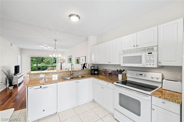 kitchen with sink, white appliances, light tile floors, and kitchen peninsula