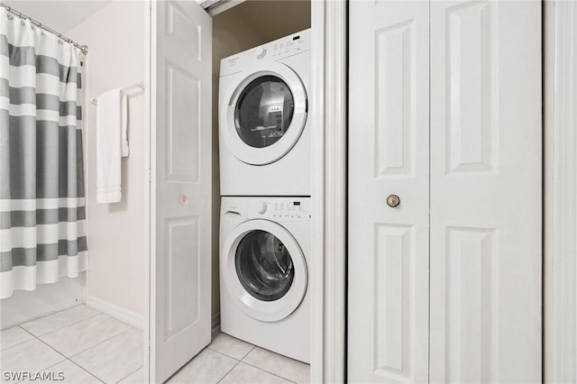 laundry area with light tile patterned flooring and stacked washer / dryer