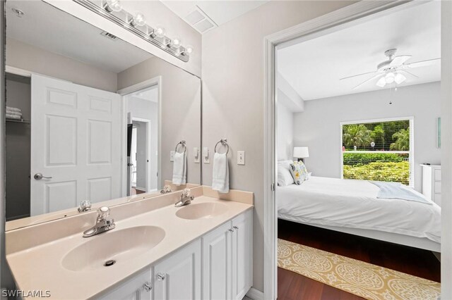 bathroom with wood-type flooring, oversized vanity, dual sinks, and ceiling fan