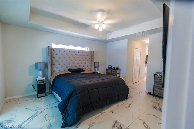 bedroom featuring ceiling fan, a tray ceiling, and a closet