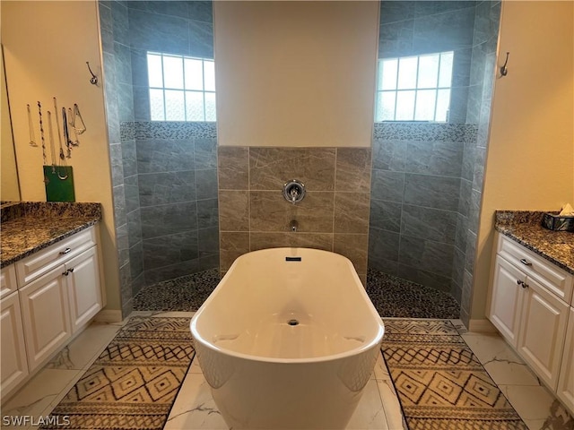 bathroom with a tub, plenty of natural light, tile walls, and vanity