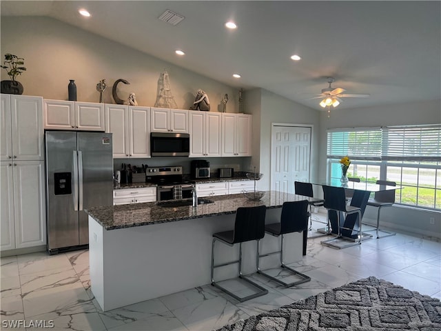 kitchen featuring white cabinetry, a kitchen island with sink, appliances with stainless steel finishes, and lofted ceiling