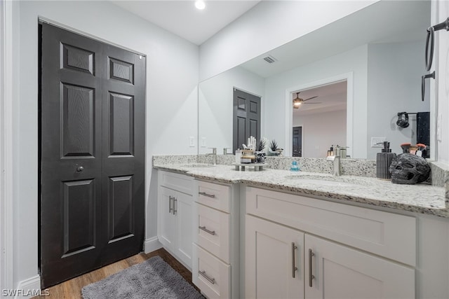 bathroom featuring wood-type flooring, ceiling fan, and double vanity