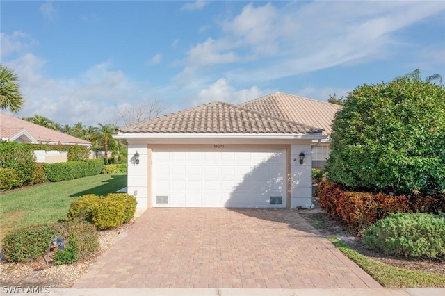 view of front of house with a garage, a tiled roof, a front lawn, and stucco siding