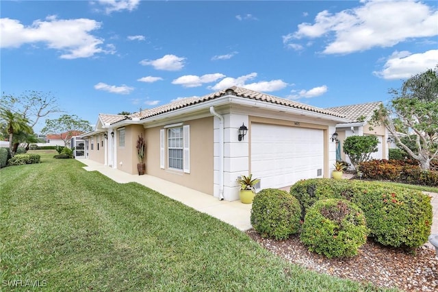 view of side of property featuring a tiled roof, a lawn, an attached garage, and stucco siding