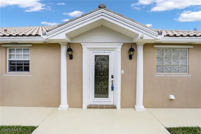 entrance to property featuring a tiled roof and stucco siding