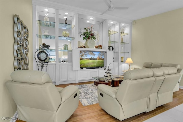 living room featuring ceiling fan, light wood-type flooring, and built in shelves